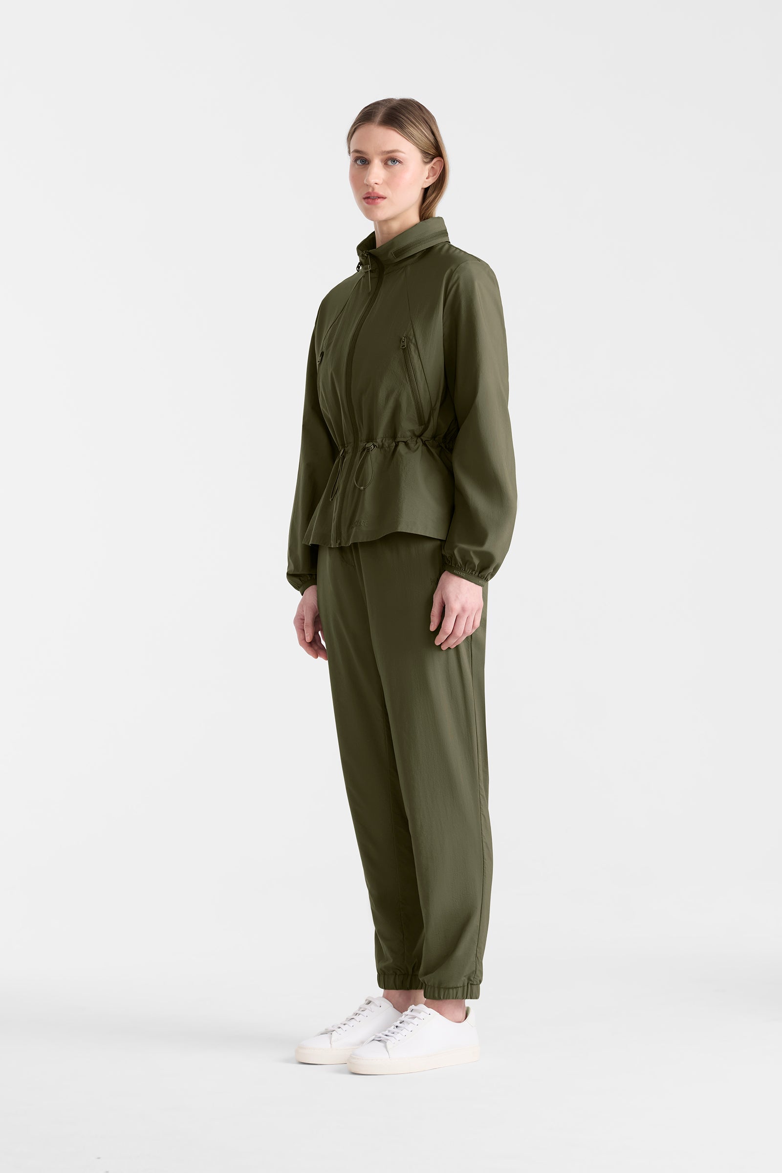 Woman wearing a light military jacket and pants on a white background