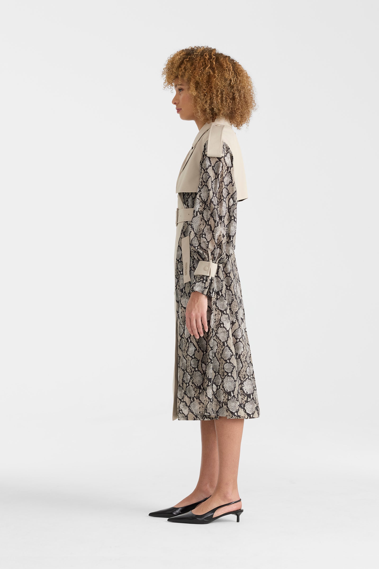 Woman wearing a lightweight snake pattern trench coat on a white background.