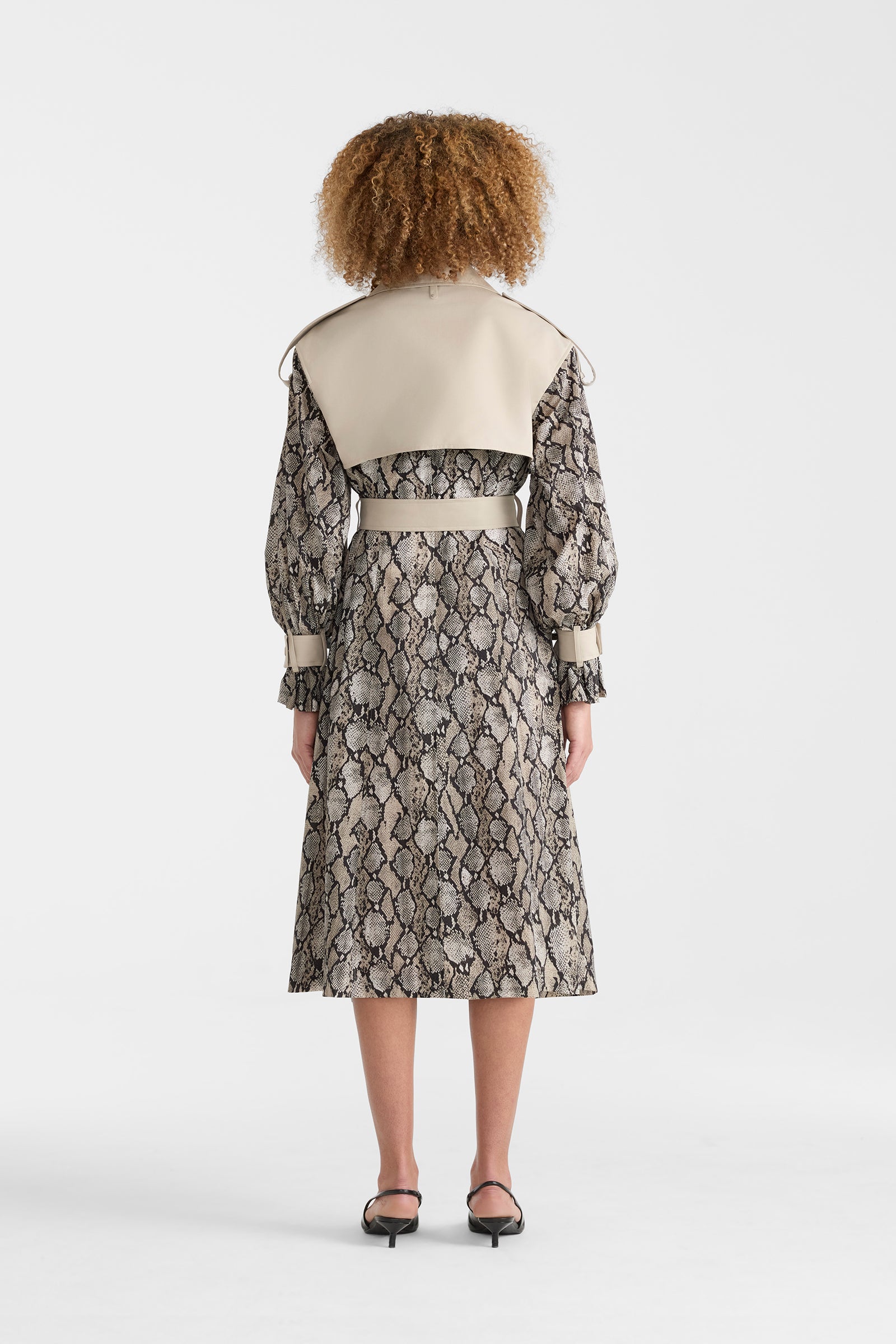 Woman wearing a lightweight snake pattern trench coat on a white background.