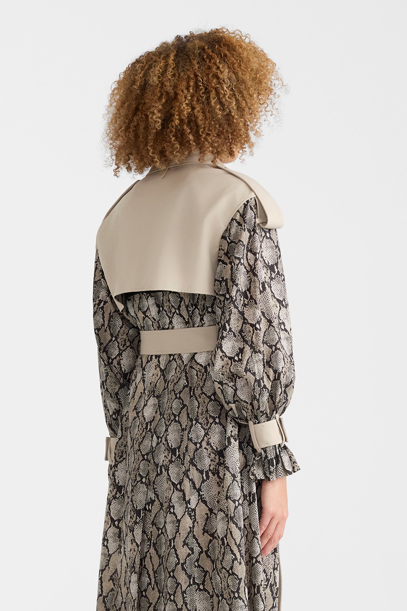 Woman wearing a lightweight snake pattern trench coat on a white background.