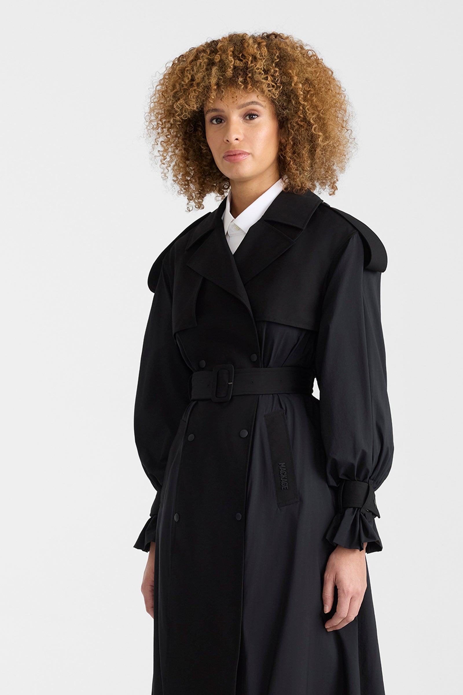 Woman wearing a black lightweight trench coat on a white background.