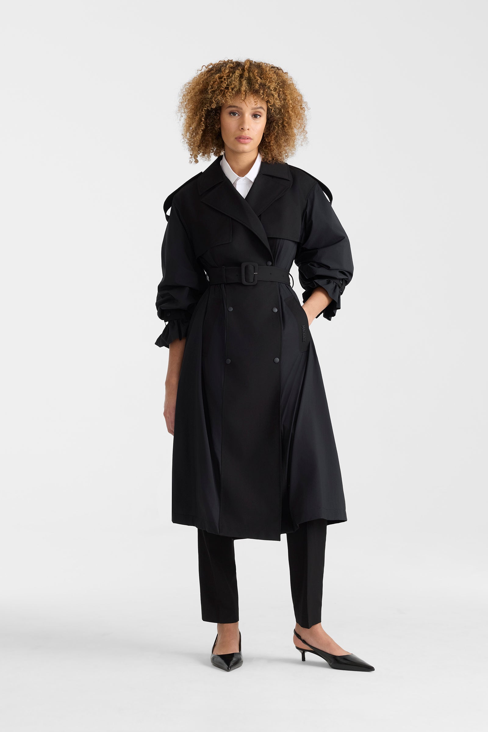 Woman wearing a black lightweight trench coat on a white background.